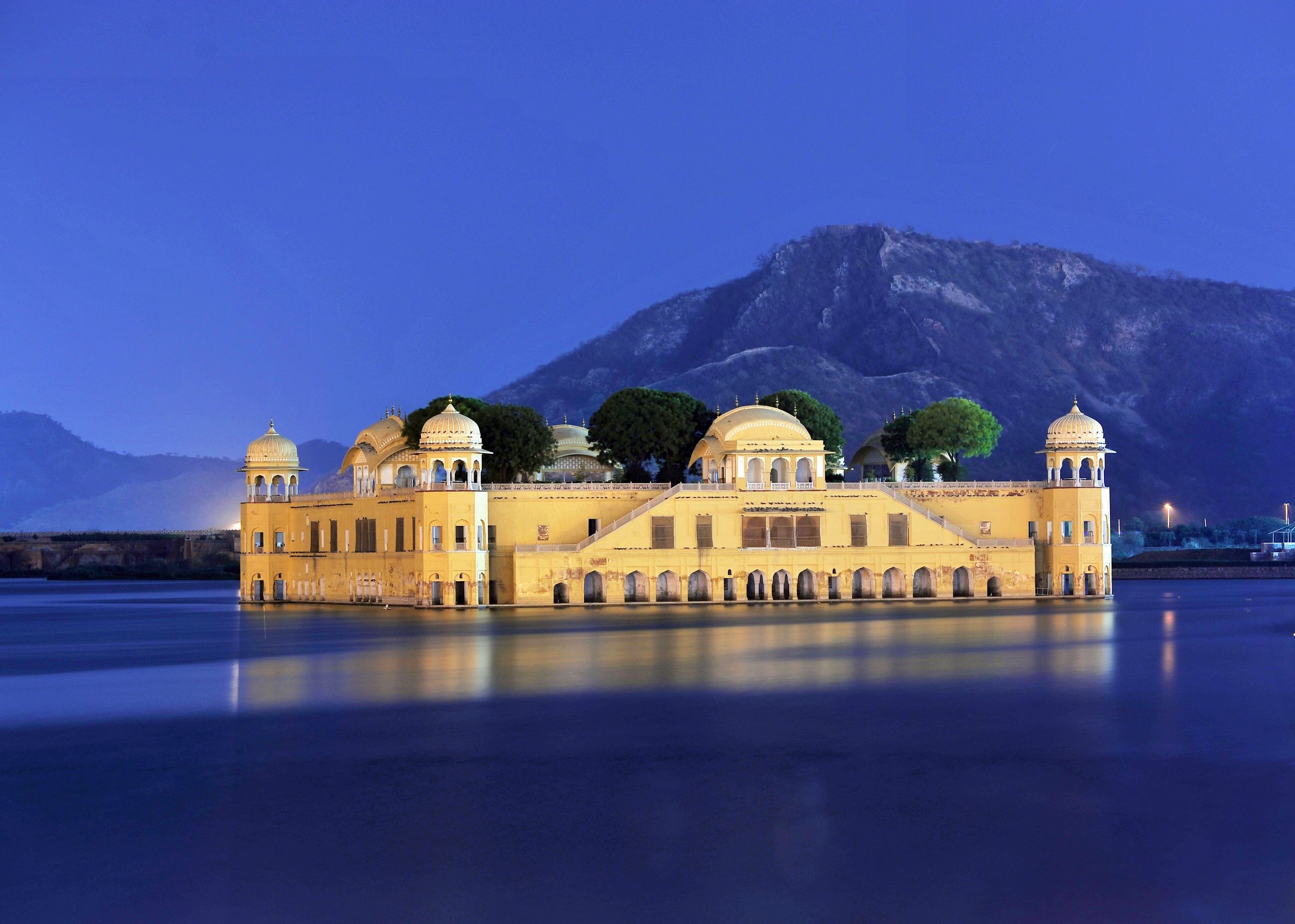 The Water Palace glowing yellow on a still lake