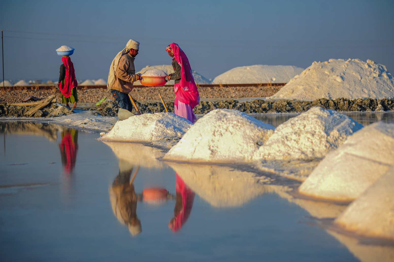 Workers among white salt heaps